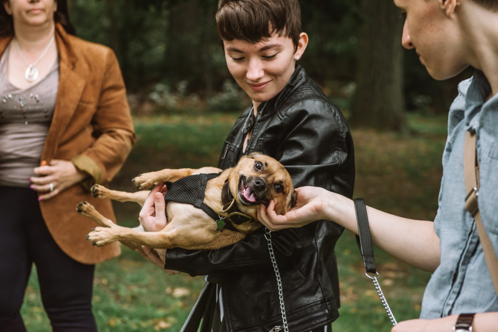 Danielle in a black leather jacket holding Milo sideways. He is smiling at the camera while she is softly smiling at Milo.