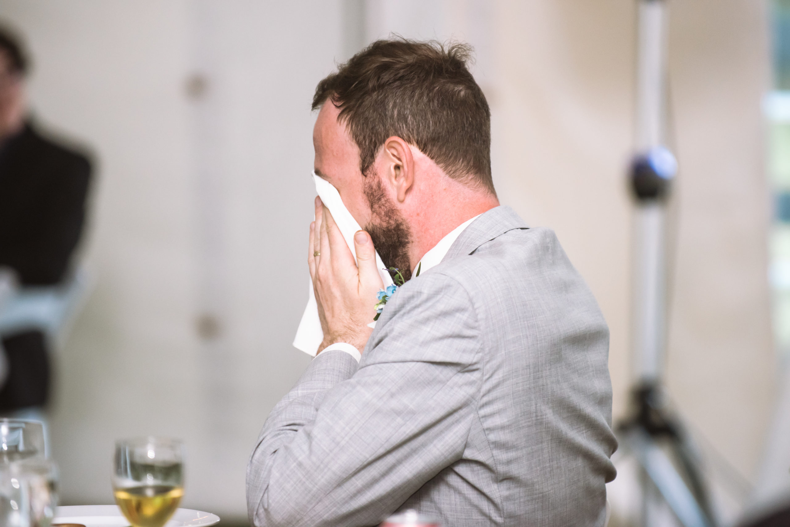 The groom holding a white napkin up to his face from tearing up at a speech during the reception.