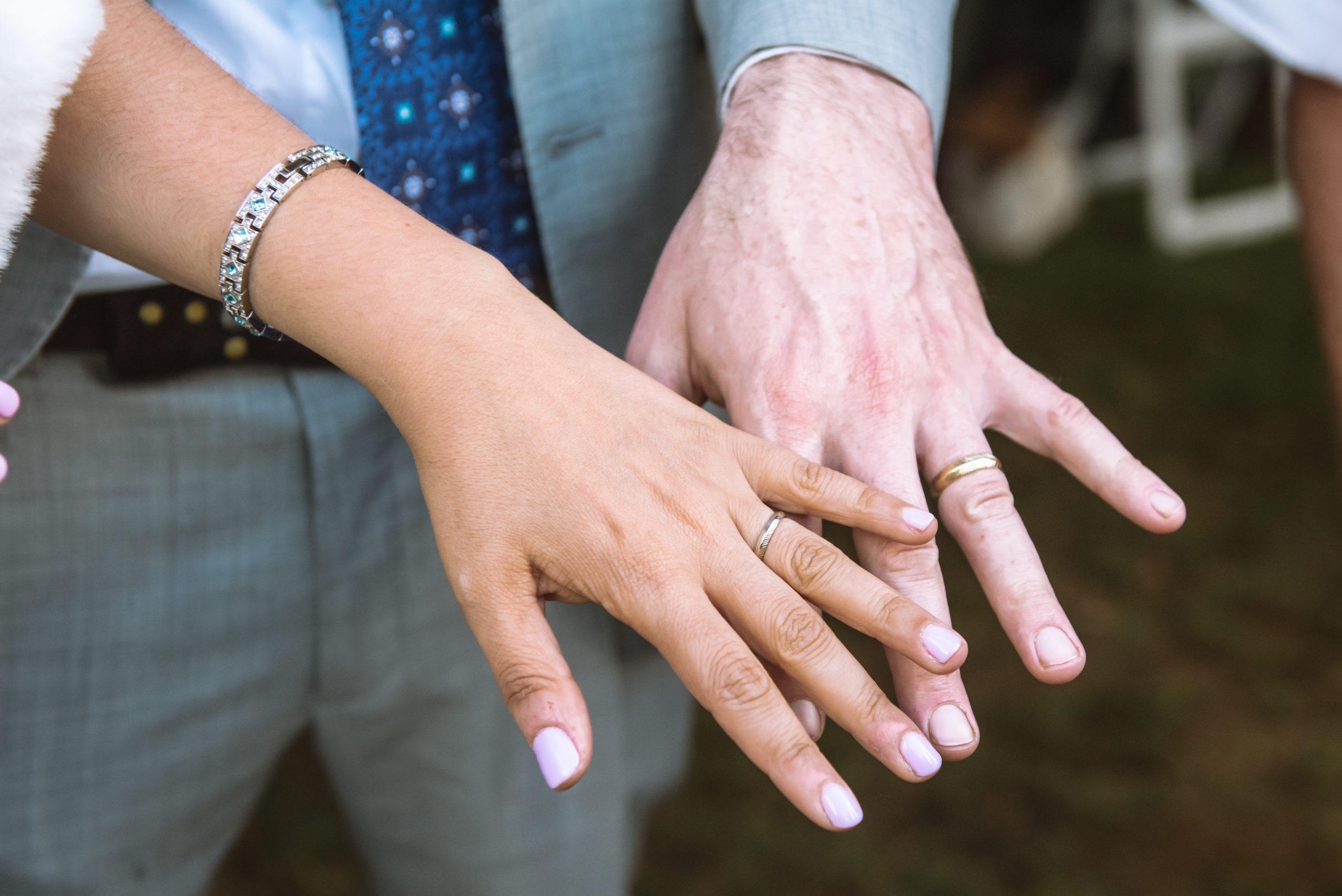 Close up photo of the bride and groom's hands showing off their rings.