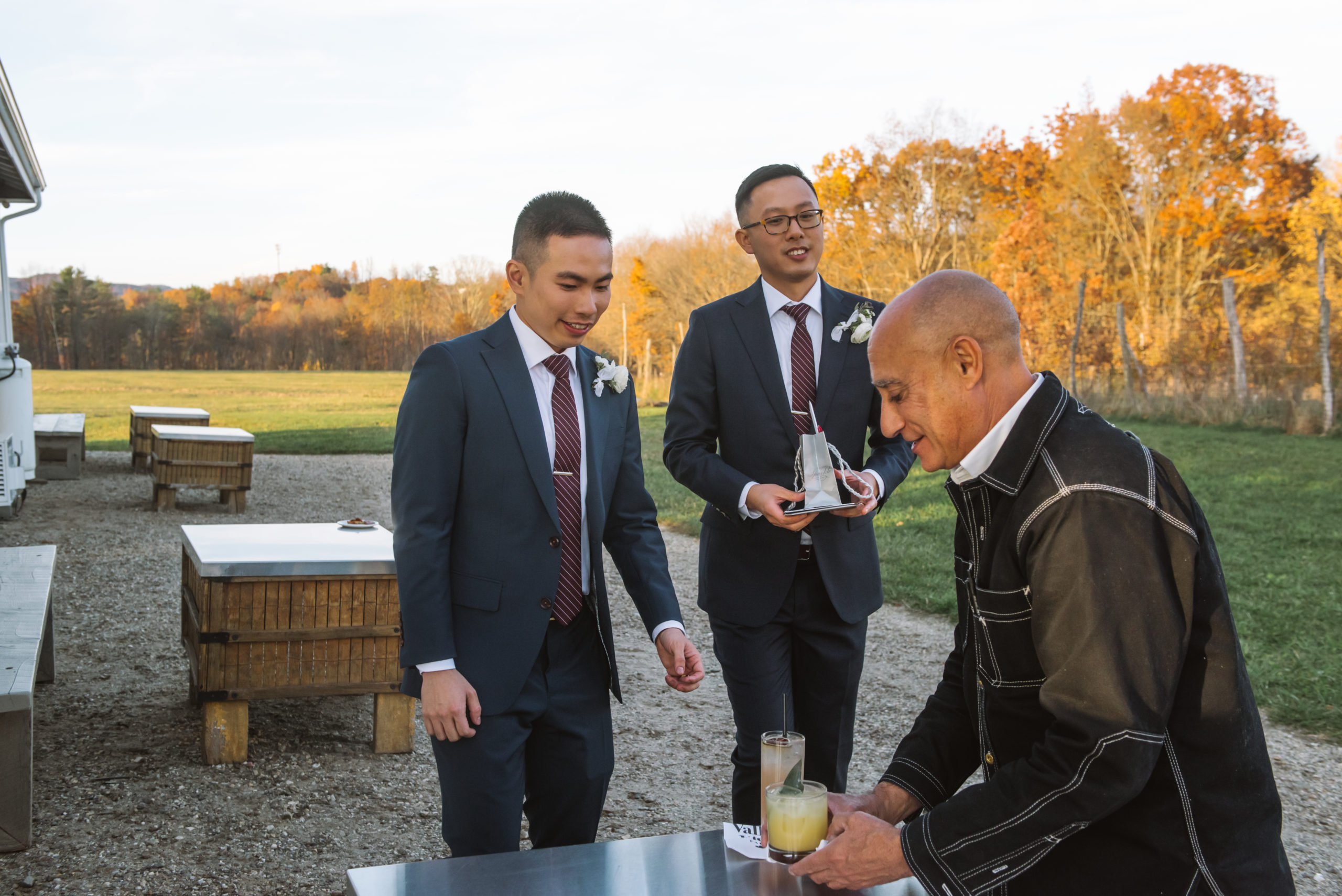 Two grooms about to receive their signature cocktails from their wedding planner.