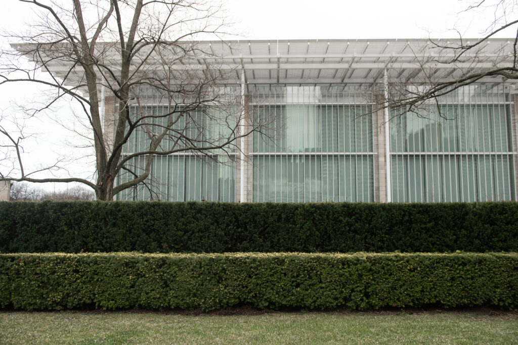 Facade of the Chicago Institute of Art with trees, hedges, and grass in the foreground.