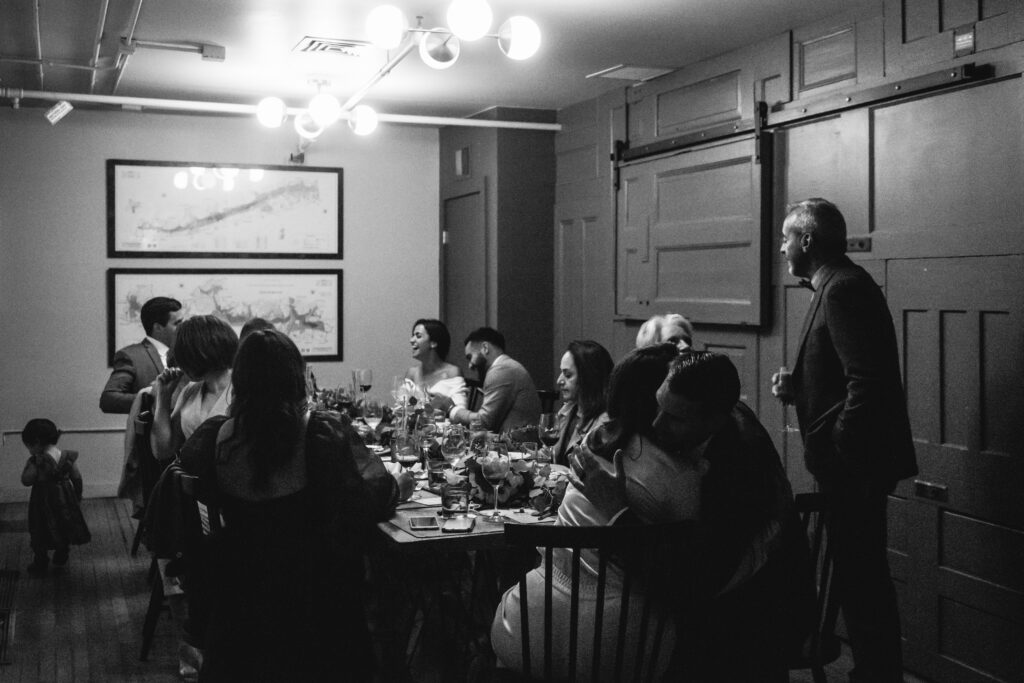 Black and white photo of intimate wedding reception with one table and 12 wedding attendees