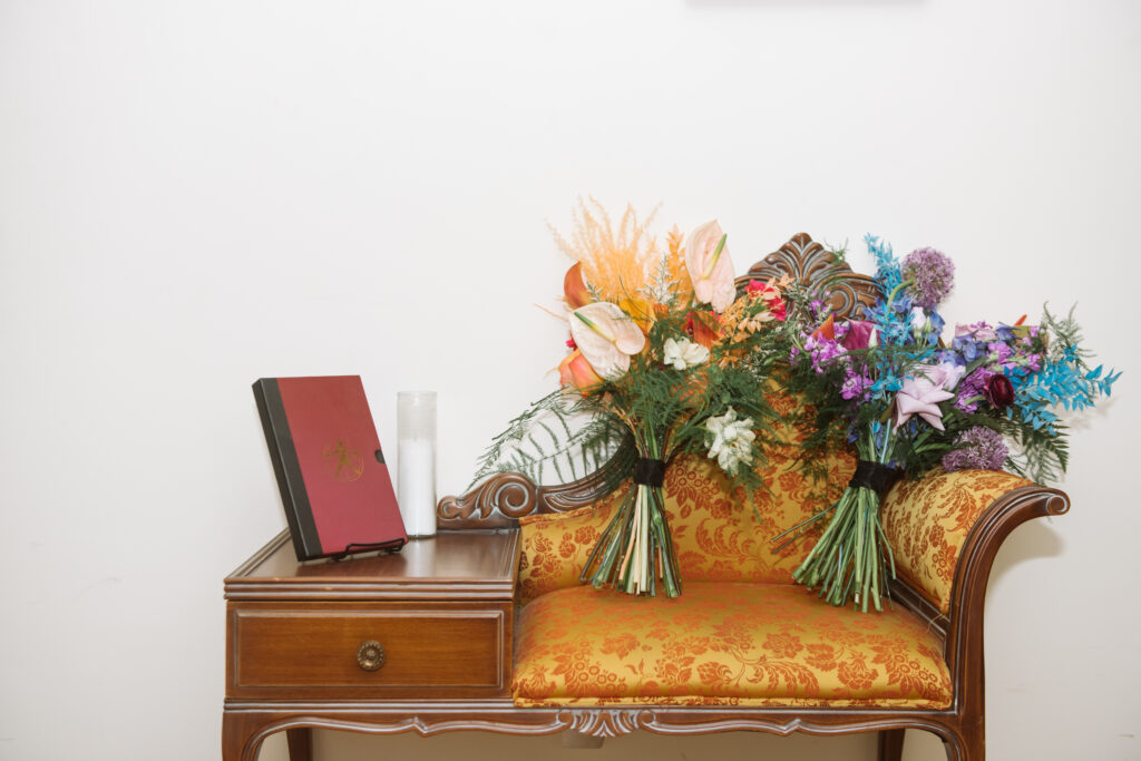 2 colorful bouquets, one orange and one blue/purple, sit on a small chair. 