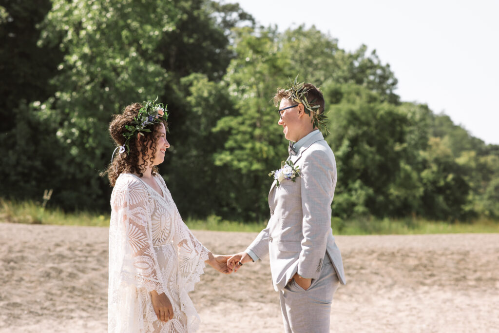 Two wedding celebrants face one another on a beach. 